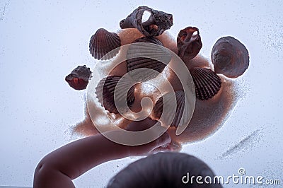 Babyâ€™s hand, sand and seashells on light table. Stock Photo